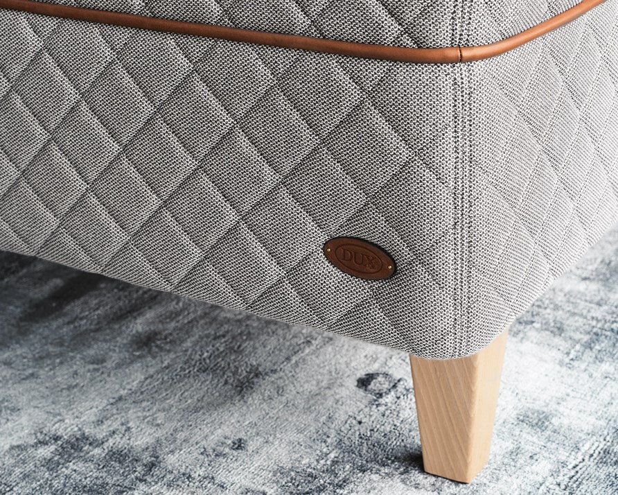 Detail of the DUX 3003 bed and tapered bed legs on a light green carpet.